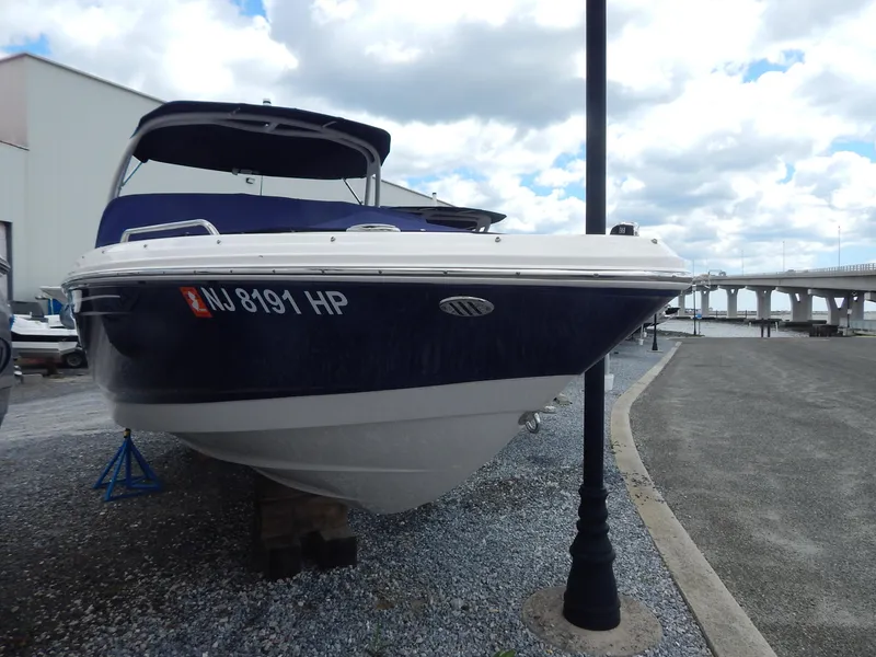 Slide: The Image of 2021 Chaparral 23 SSi boat on display near a waterfront, under a cloudy sky. - 0