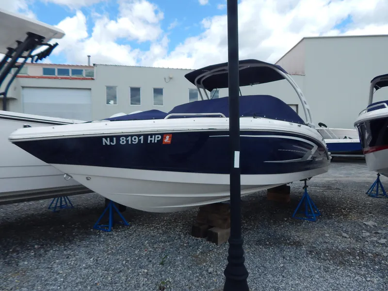 Slide: The Image of 2021 Chaparral 23 SSi boat on stands, blue and white hull, outdoor storage. - 1