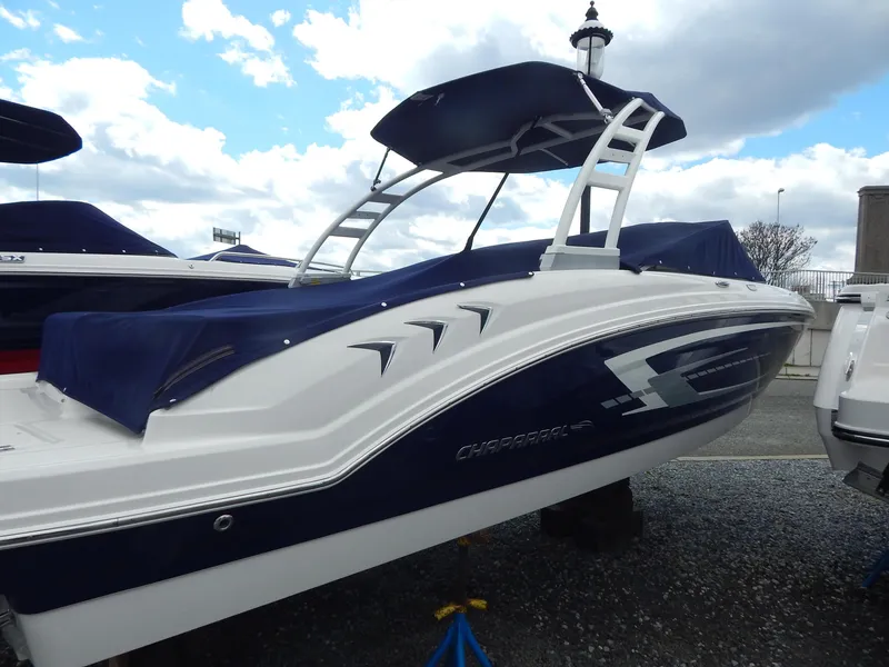 Slide: The Image of 2021 Chaparral 23 SSi boat with blue cover and sleek design, displayed outdoors. - 2