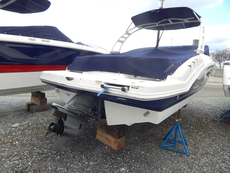 Slide: The Image of 2021 Chaparral 23 SSi boat with blue cover, displayed on stands. - 3