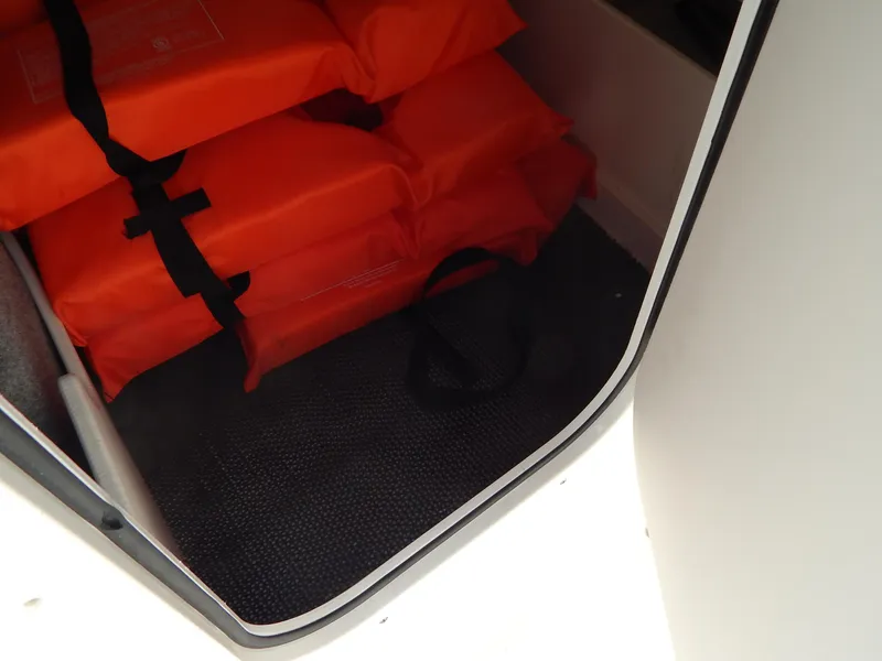 Slide: The Image of Storage compartment with orange life jackets in a 2021 Chaparral 23 SSi boat. - 40