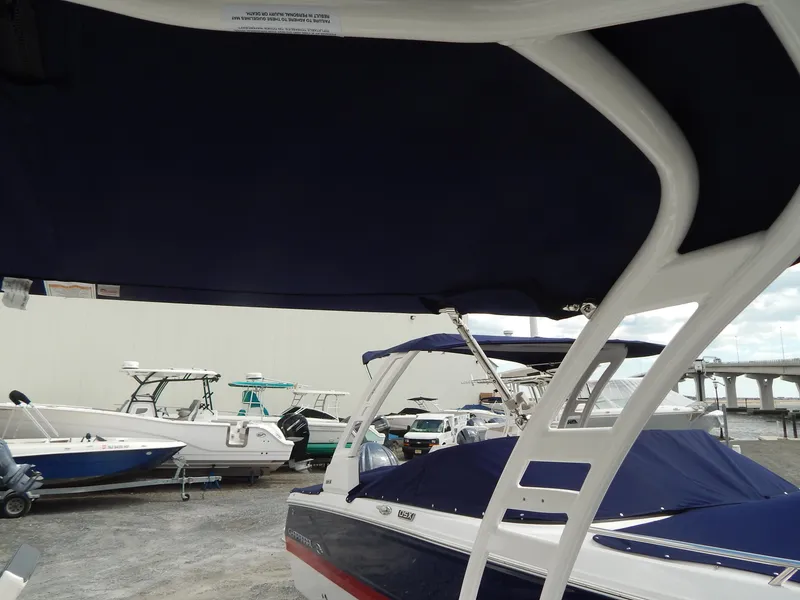 Slide: The Image of 2021 Chaparral 23 SSi boat with blue canopy, docked near other boats. - 42