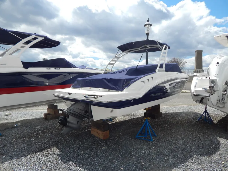 Slide: The Image of 2021 Chaparral 23 SSi boat on stands, covered, with cloudy sky background. - 45