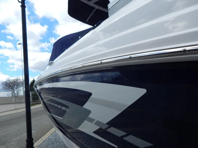 Slide: The Image of 2021 Chaparral 23 SSi boat with sleek design and modern graphics under a cloudy sky. - 6