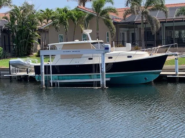 Slide: The Image of 2008 Mainship Pilot 34 docked near waterfront homes with palm trees. - 1