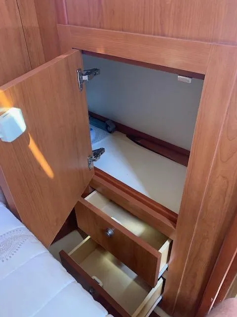Slide: The Image of 2008 Mainship Pilot 34 interior storage with open wooden cabinets and drawers. - 10