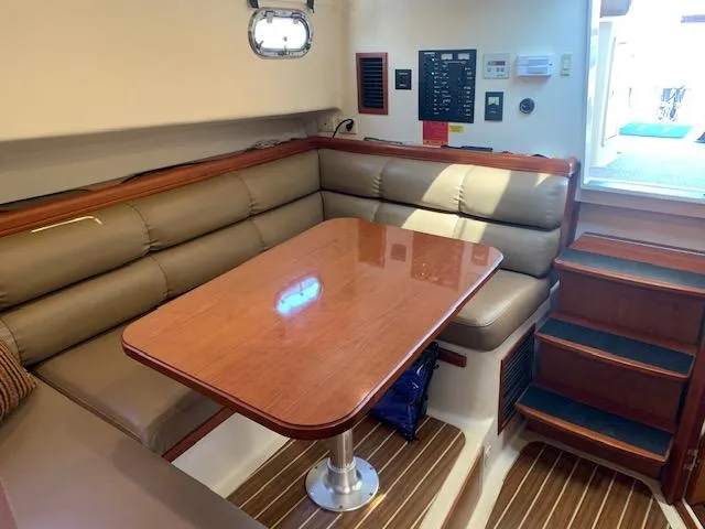 Slide: The Image of 2008 Mainship Pilot 34 interior with cushioned seating and wooden table. - 12