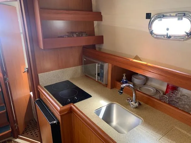 Slide: The Image of 2008 Mainship Pilot 34 galley with sink, stove, microwave, and storage shelves. - 15