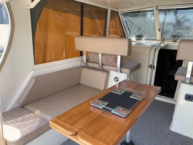 Slide: The Image of 2008 Mainship Pilot 34 interior with seating and wooden table, featuring large windows. - 3
