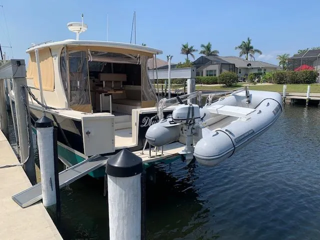 Slide: The Image of 2008 Mainship Pilot 34 docked with inflatable dinghy, in a sunny marina setting. - 30