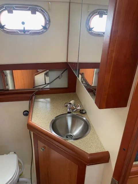 Slide: The Image of 2008 Mainship Pilot 34 bathroom with sink, mirror, and porthole window. - 7