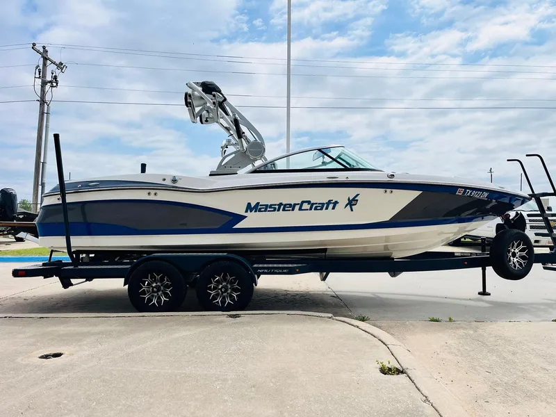 Slide: The Image of 2016 MasterCraft X30 boat on trailer, side view, blue and white design, parked outdoors. - 4