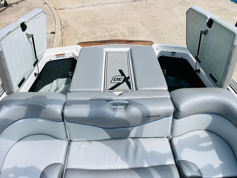Slide: The Image of 2016 MasterCraft X30 boat interior with open storage compartments and cushioned seating. - 43