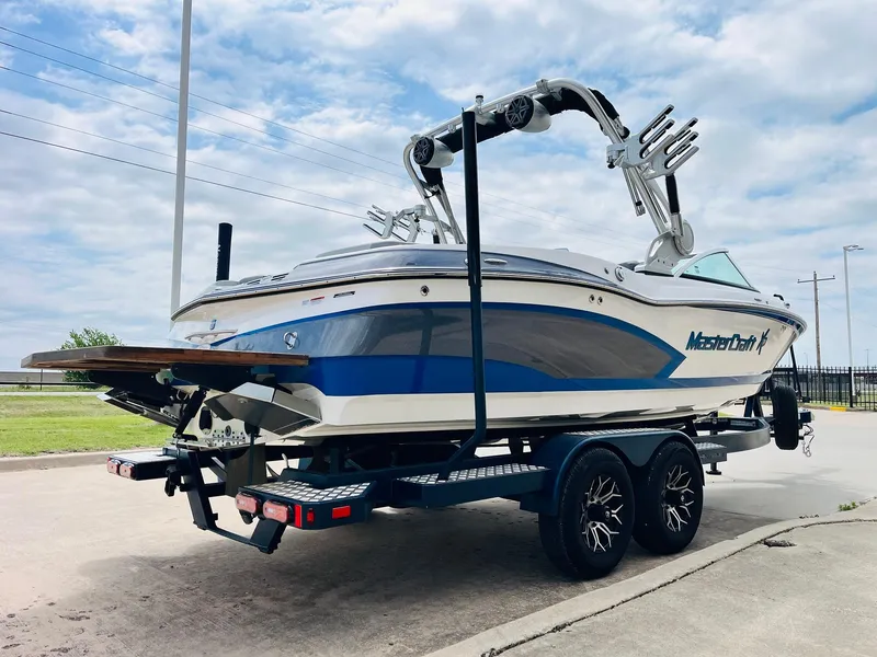 Slide: The Image of 2016 MasterCraft X30 boat on trailer, blue and white design, parked outdoors. - 5