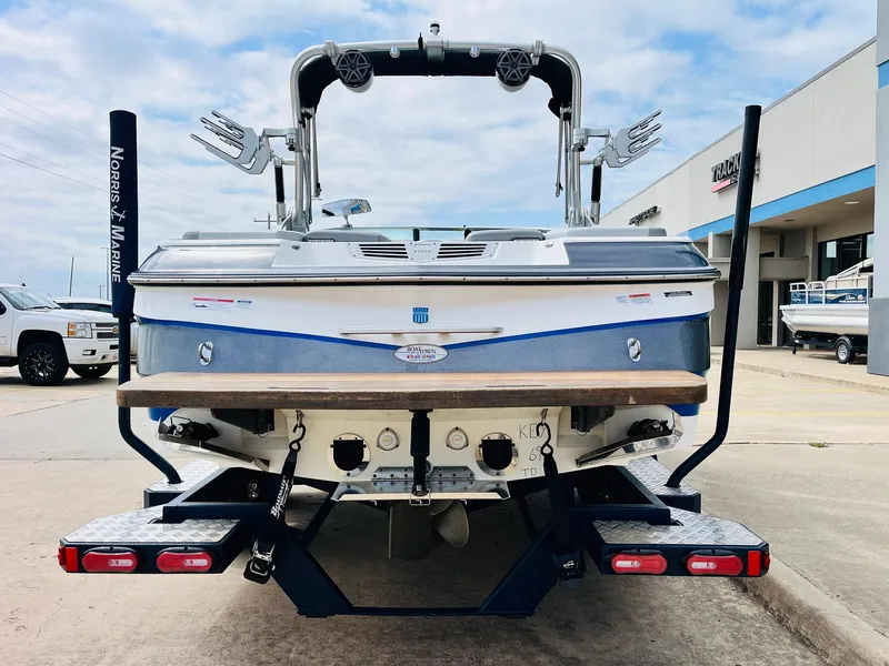 Slide: The Image of 2016 MasterCraft X30 boat rear view at marina, showcasing wakeboard tower and swim platform. - 6