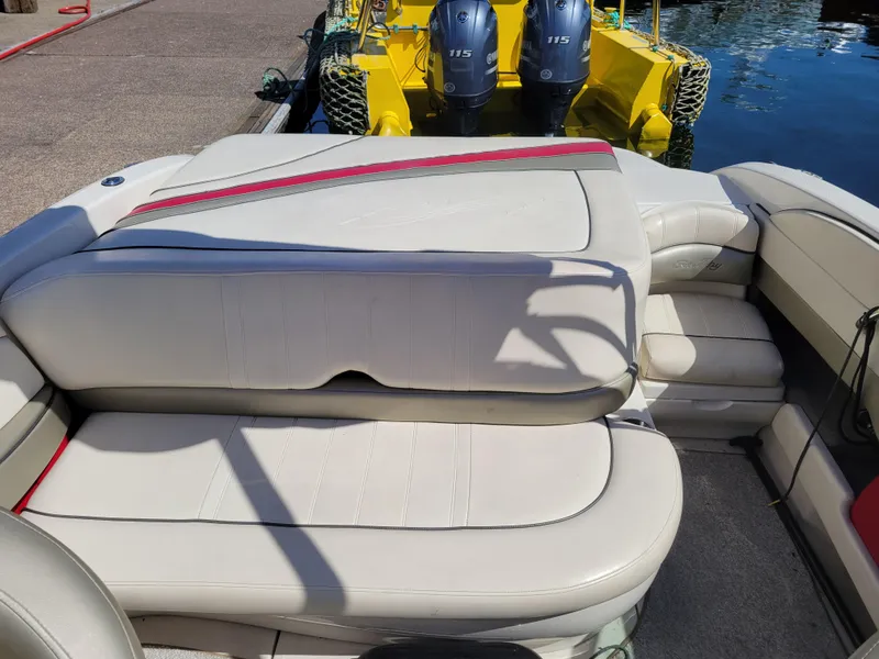 Slide: The Image of 2005 Sea Ray 200 Select boat interior with beige seating and red accents, docked by the water. - 18