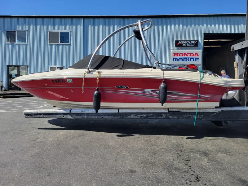 Slide: The Image of 2005 Sea Ray 200 Select boat in red, docked at a marina with blue building background. - 25