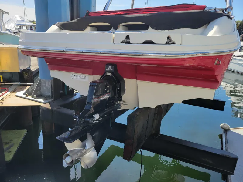 Slide: The Image of 2005 Sea Ray 200 Select boat on lift, red and white hull, outboard motor visible. - 27