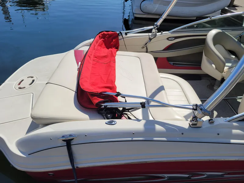 Slide: The Image of 2005 Sea Ray 200 Select boat with red and white seating, docked on calm water. - 6