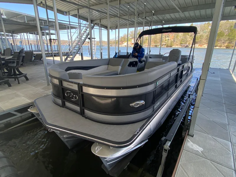 Slide: The Image of 2021 Manitou 25 Encore RF SHP Twin pontoon boat docked in a covered marina. - 11
