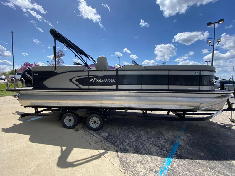 Slide: The Image of 2021 Manitou 25 Encore RF SHP Twin pontoon boat on a trailer under a blue sky. - 17