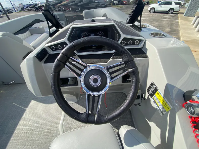 Slide: The Image of Steering wheel of 2021 Manitou 25 Encore RF SHP Twin boat, featuring modern dashboard controls. - 33