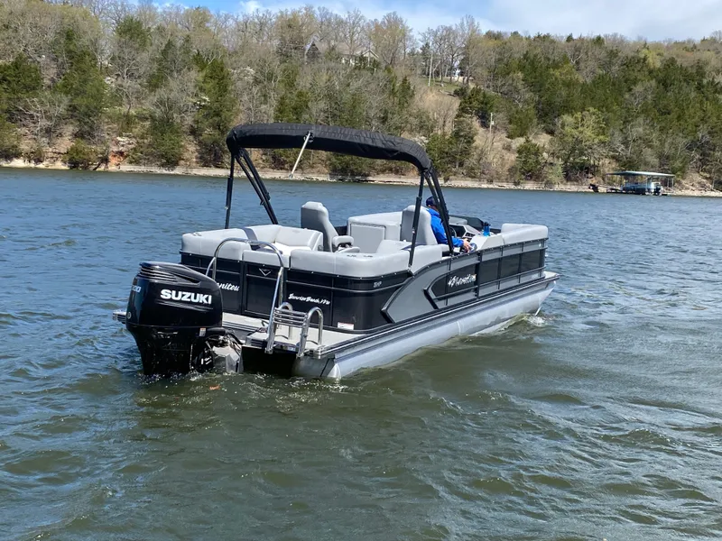 Slide: The Image of 2021 Manitou 25 Encore RF SHP Twin pontoon boat on a lake with Suzuki outboard motor. - 8