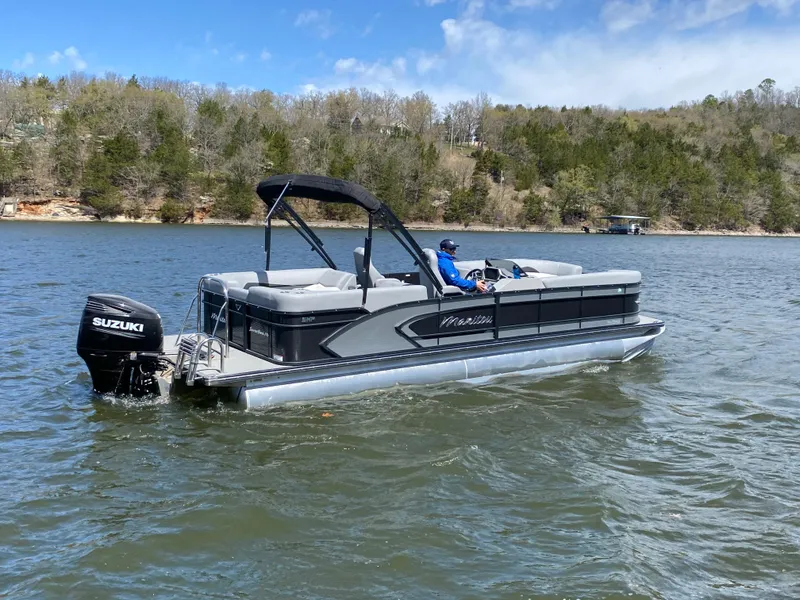 Slide: The Image of 2021 Manitou 25 Encore RF SHP Twin pontoon boat on a lake with trees in the background. - 9