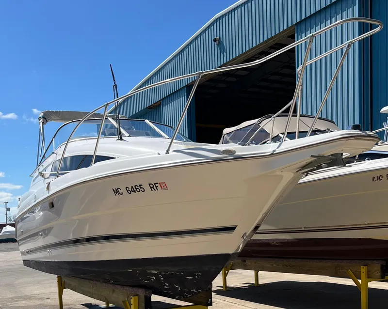 Slide: The Image of 1997 Bayliner 2655 Ciera Sunbridge boat docked near a blue warehouse. - 2