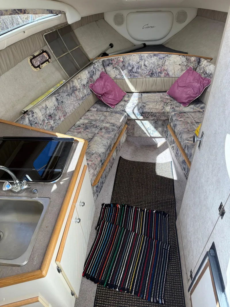 Slide: The Image of 1997 Bayliner 2655 Ciera Sunbridge cabin interior with kitchenette, seating, and colorful rug. - 22