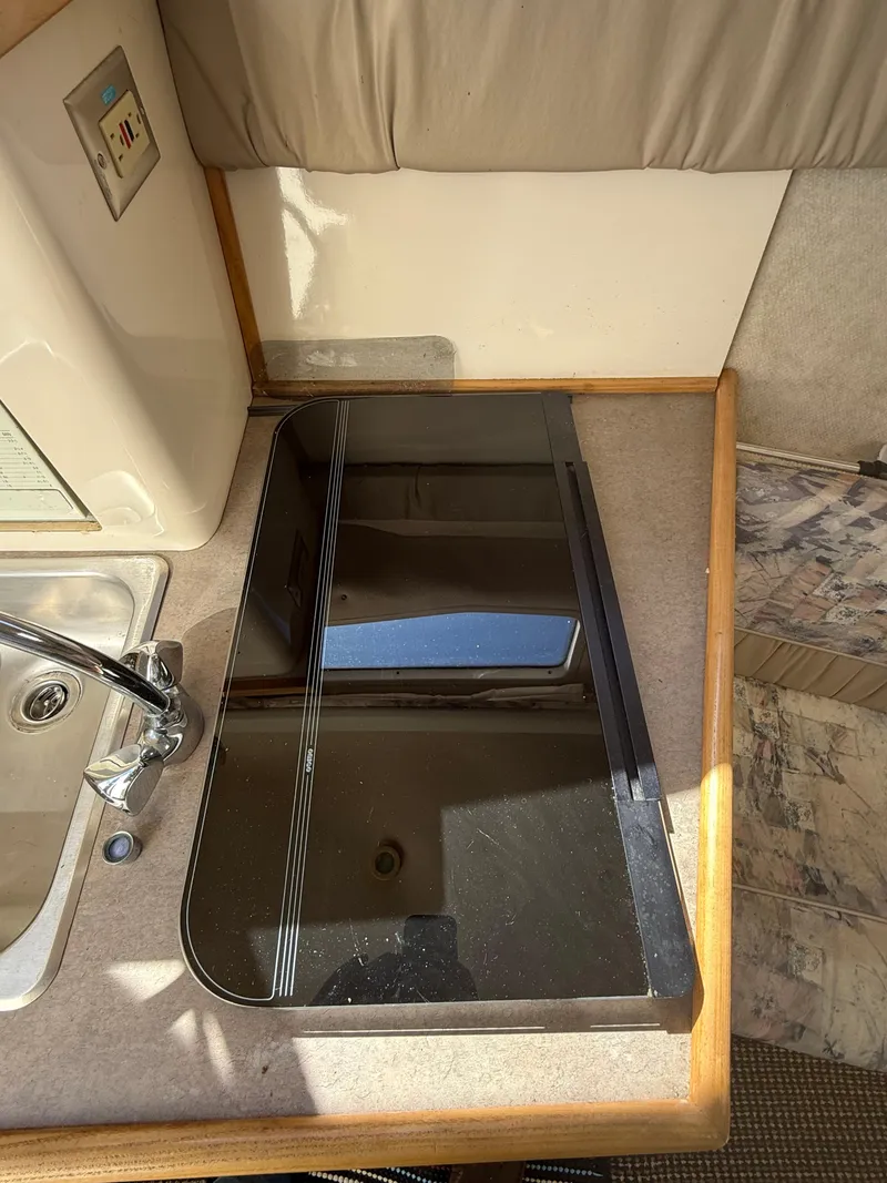 Slide: The Image of 1997 Bayliner 2655 Ciera Sunbridge interior kitchen area with sink and stove. - 24