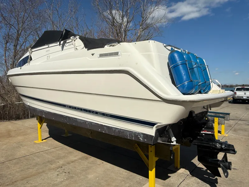 Slide: The Image of 1997 Bayliner 2655 Ciera Sunbridge boat on stands, outdoors, under clear blue sky. - 5