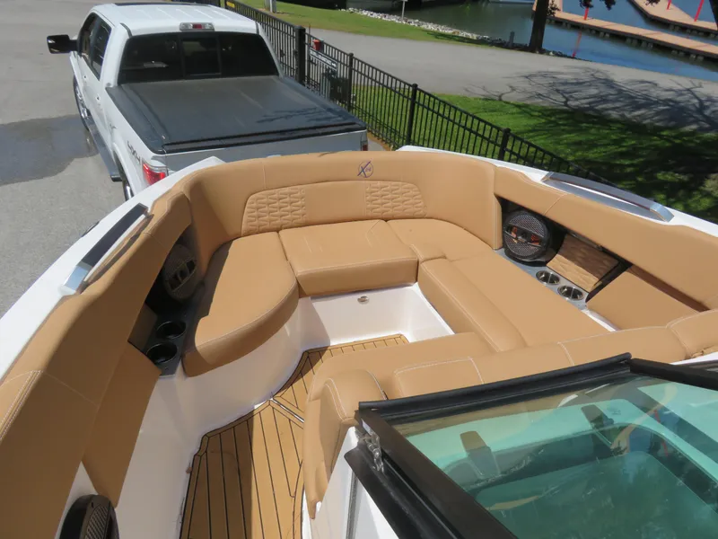 Slide: The Image of 2023 MasterCraft X26 boat with tan seating, docked near a white truck. - 4