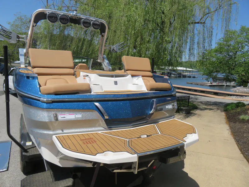 Slide: The Image of 2023 MasterCraft X26 boat with tan seating, docked near a lake under clear skies. - 9