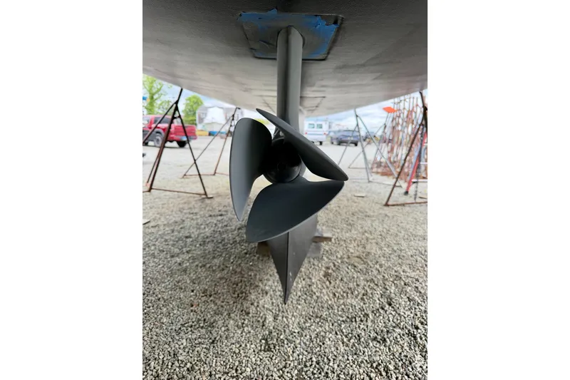 Slide: The Image of Propeller of 2022 Elan Impression 50.1 sailboat on gravel, supported by stands. - 102