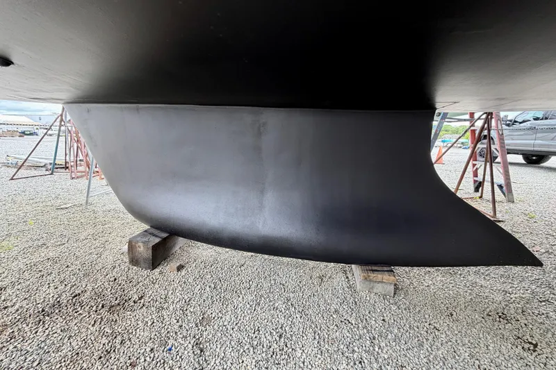 Slide: The Image of 2022 Elan Impression 50.1 yacht keel on gravel, supported by wooden blocks. - 104
