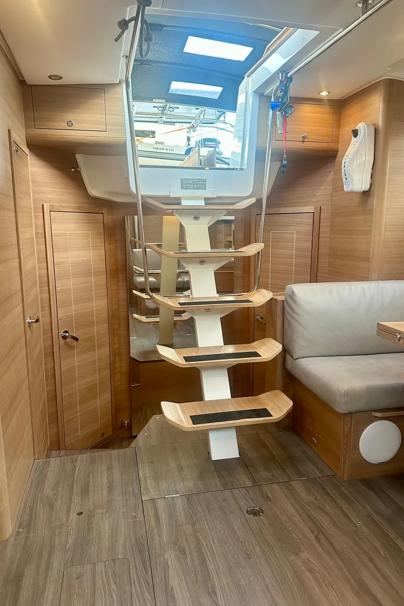 Slide: The Image of 2022 Elan Impression 50.1 yacht interior with modern wooden staircase and seating area. - 38