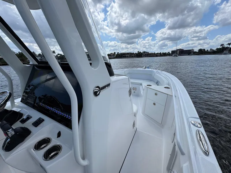 Slide: The Image of 2023 Edgewater 262CC boat interior with console, on a sunny day by the water. - 10