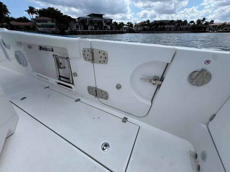 Slide: The Image of 2023 Edgewater 262CC boat interior, featuring storage compartments and sleek design by the water. - 14