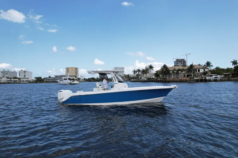 Slide: The Image of 2023 Edgewater 262CC boat cruising on a sunny day near waterfront buildings. - 3