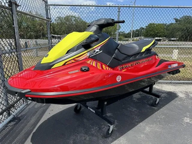 Slide: The Image of 2024 Yamaha WaveRunner EX in vibrant red and yellow, displayed outdoors on a stand. - 2
