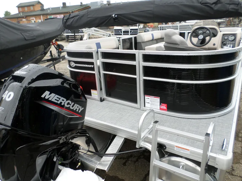Slide: The Image of 2024 Princecraft Jazz 170 pontoon boat with Mercury engine, docked and covered. - 2