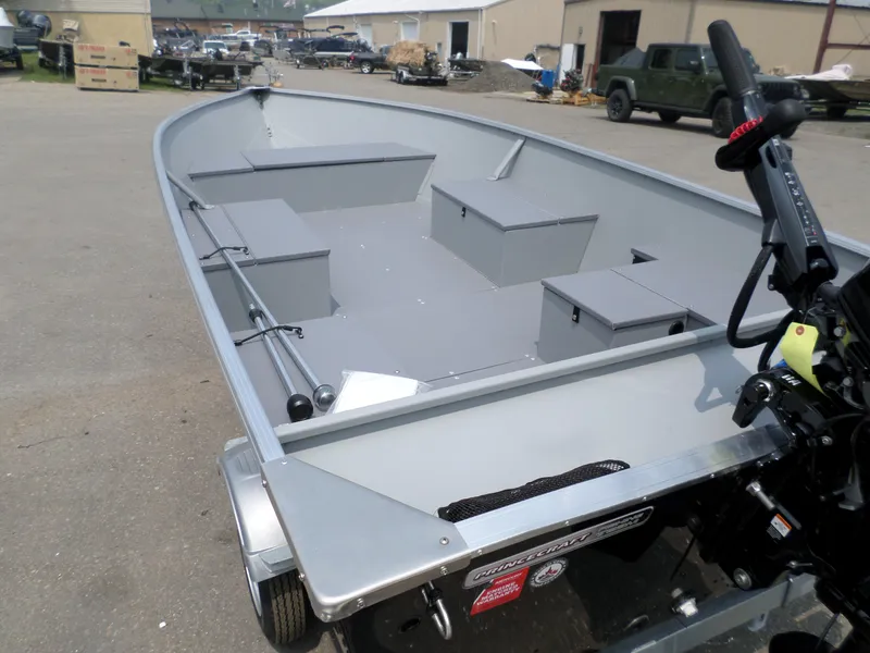 Slide: The Image of 2023 Princecraft Yukon 140 boat with motor, parked outdoors, showcasing interior seating and storage. - 4