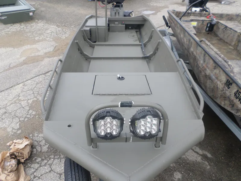 Slide: The Image of 2024 Gator Trax 1544 boat with dual front lights, parked on a textured surface. - 2