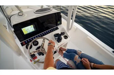 Slide: The Image of 2022 Sea Hunt Ultra 229 boat dashboard with GPS and steering wheel on calm water. - 15