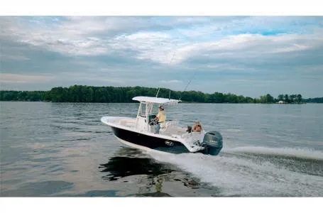Slide: The Image of 2022 Sea Hunt Ultra 229 boat cruising on a calm lake under a cloudy sky. - 16