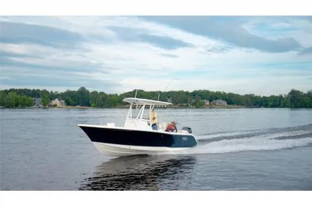 Slide: The Image of 2022 Sea Hunt Ultra 229 boat cruising on a calm lake under a cloudy sky. - 19