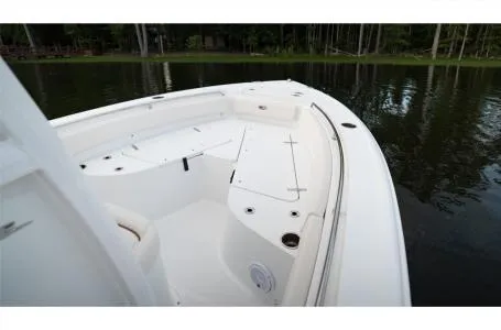 Slide: The Image of 2022 Sea Hunt Ultra 229 boat, spacious deck, calm water, forested shoreline. - 21