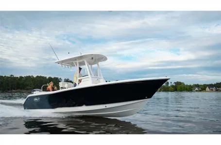 Slide: The Image of 2022 Sea Hunt Ultra 229 boat cruising on a calm lake under a cloudy sky. - 22