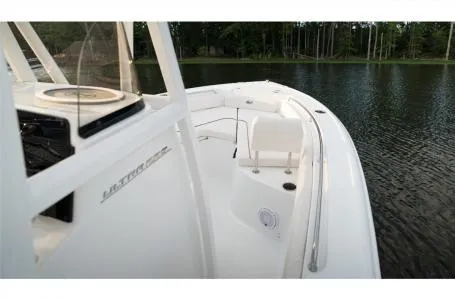 Slide: The Image of 2022 Sea Hunt Ultra 229 boat on calm water, showcasing sleek design and spacious deck. - 24